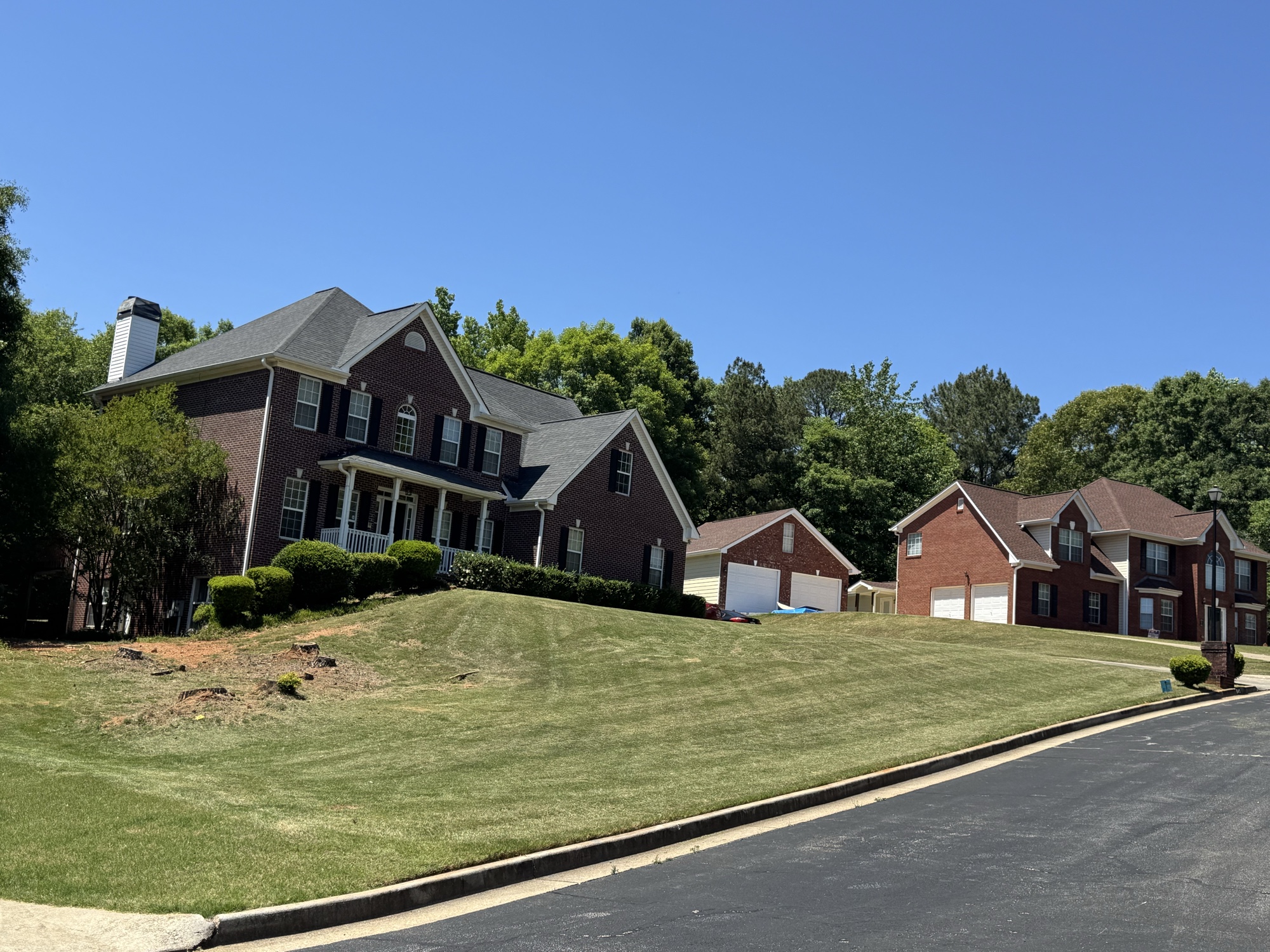 Large mowed lawn at brick two-story home with mowing stripes
