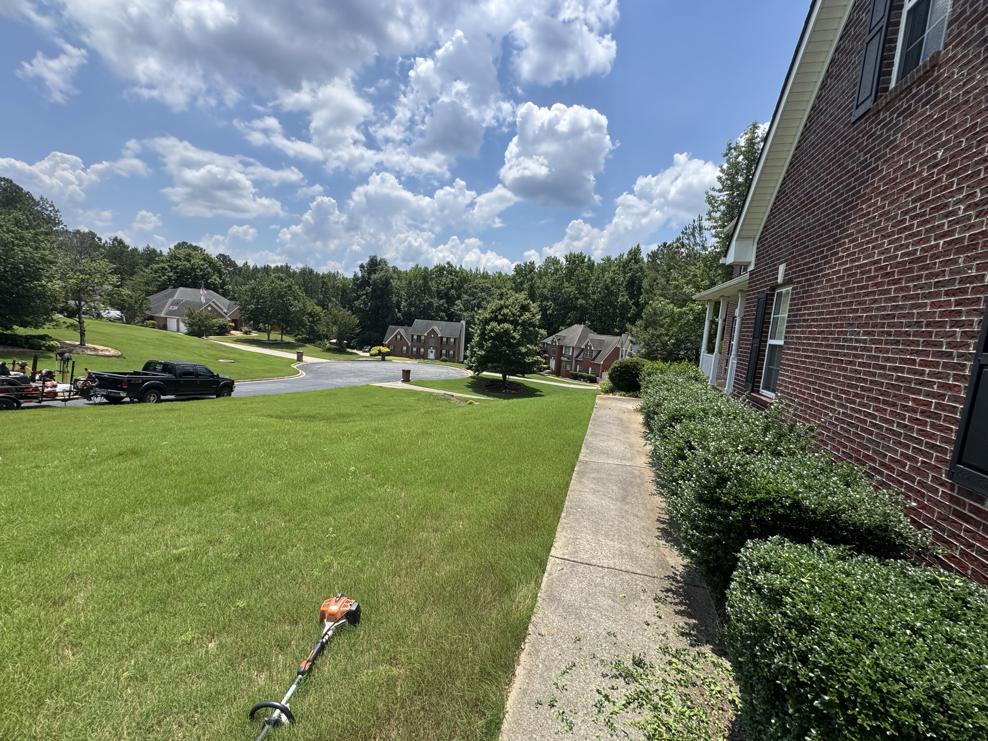 Mowed hillside lawn next to brick house